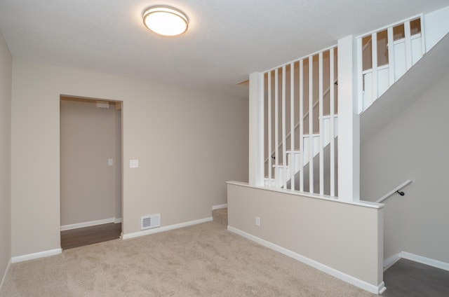 empty room with carpet floors, visible vents, and baseboards