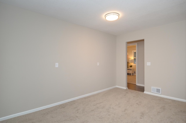 carpeted spare room featuring visible vents and baseboards