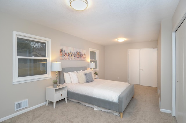 carpeted bedroom with a closet, visible vents, and baseboards