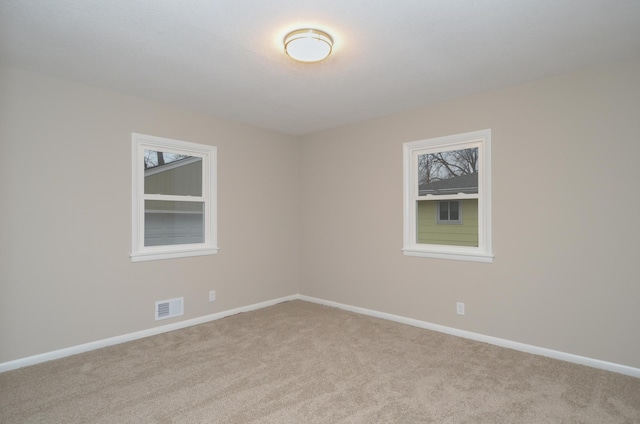 carpeted empty room featuring visible vents and baseboards