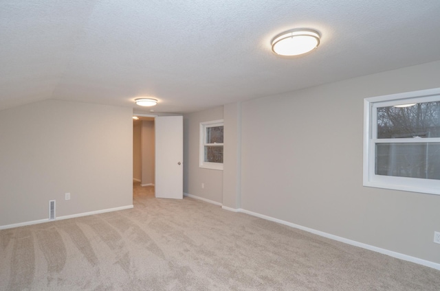 empty room with light carpet, baseboards, visible vents, and a textured ceiling