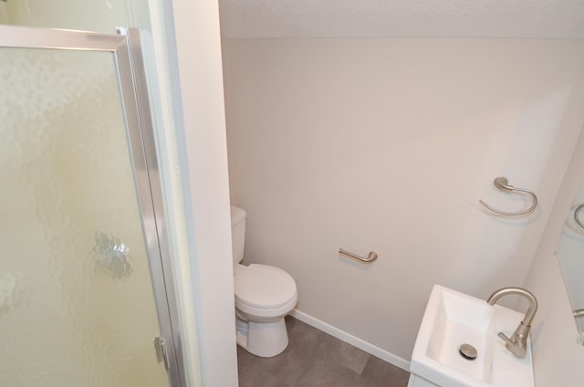 full bathroom featuring toilet, a stall shower, a textured ceiling, vanity, and baseboards