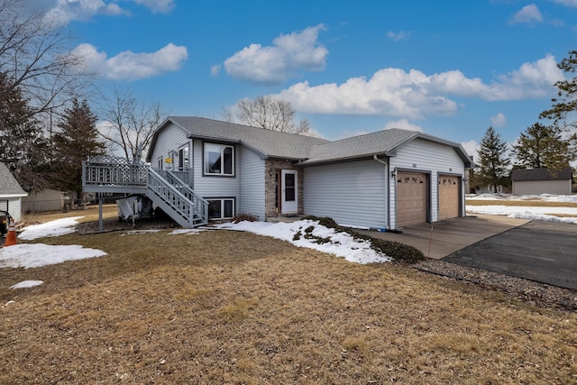 tri-level home with a deck, driveway, roof with shingles, a garage, and stairs