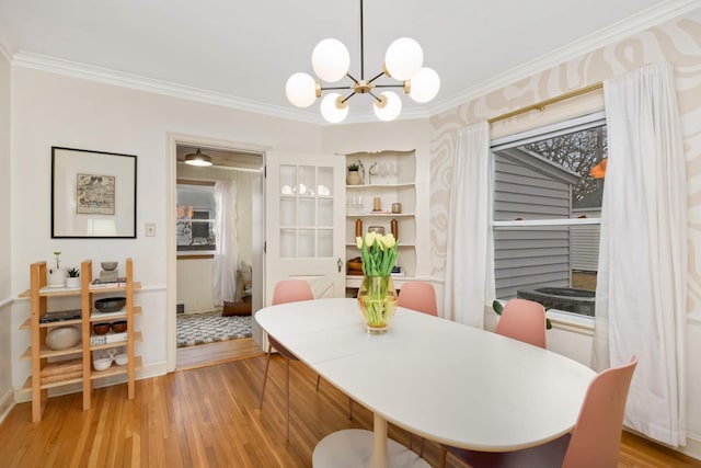 dining room with a notable chandelier, crown molding, and light wood-style flooring