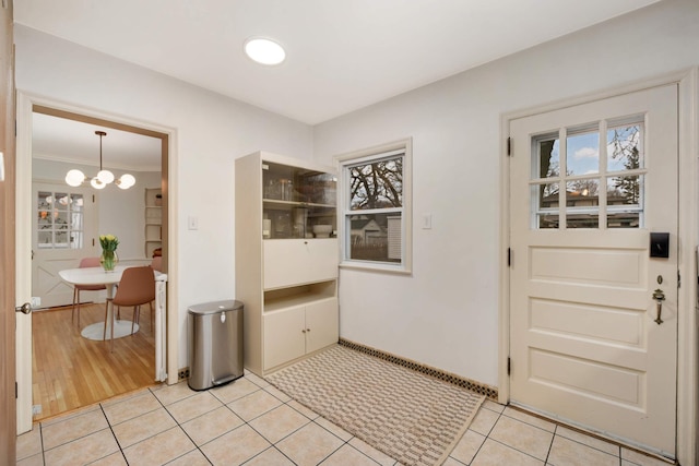 entryway featuring crown molding, an inviting chandelier, and light tile patterned floors