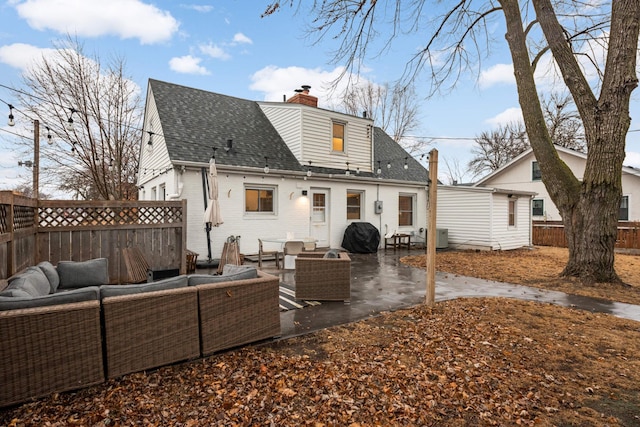 rear view of house featuring roof with shingles, a chimney, outdoor lounge area, a patio area, and a fenced backyard