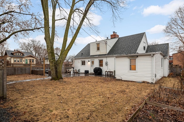 rear view of house with a shingled roof, a fenced backyard, a patio, and a chimney