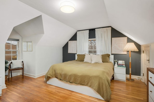 bedroom with vaulted ceiling, wood finished floors, and baseboards