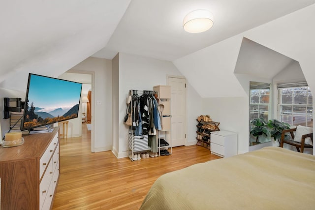 bedroom with lofted ceiling, light wood-style flooring, and baseboards