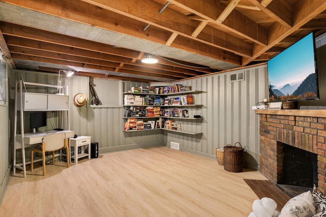 unfinished below grade area featuring a brick fireplace, visible vents, and wood finished floors