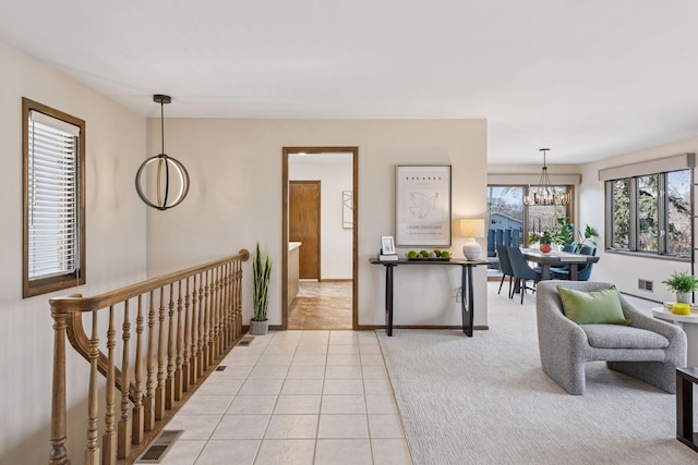 interior space with visible vents, light tile patterned floors, baseboards, light colored carpet, and a chandelier