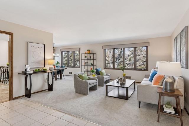 living room featuring a notable chandelier, light tile patterned floors, light colored carpet, and baseboards