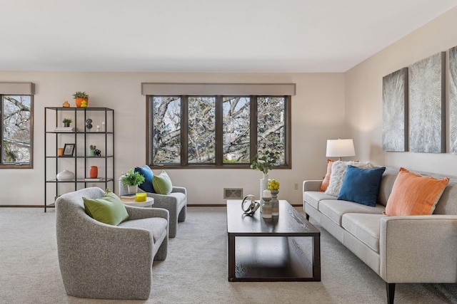 carpeted living area with plenty of natural light, baseboards, and visible vents