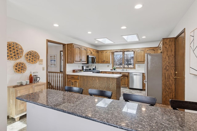 kitchen featuring a breakfast bar, a peninsula, a skylight, a sink, and stainless steel appliances