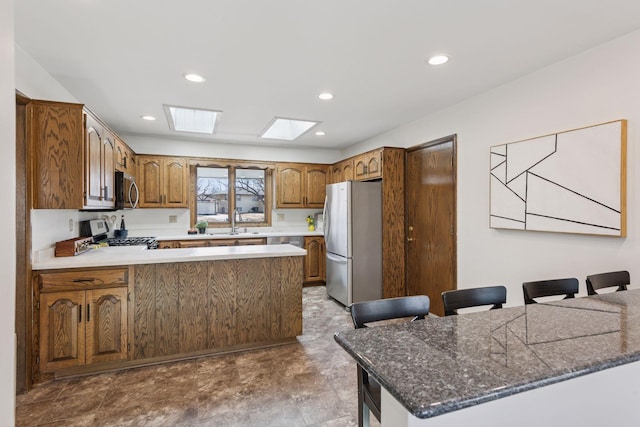 kitchen featuring a sink, recessed lighting, stainless steel appliances, a peninsula, and a skylight