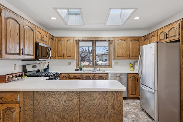 kitchen with a skylight, a peninsula, stainless steel appliances, and a sink