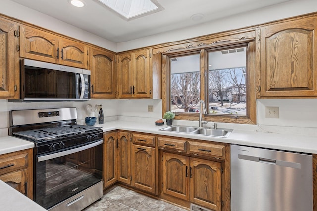 kitchen featuring a sink, stainless steel appliances, brown cabinets, and light countertops