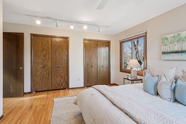 bedroom with ceiling fan, two closets, and light wood-style floors