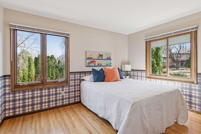 bedroom featuring a wainscoted wall and light wood finished floors