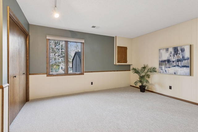 carpeted spare room featuring visible vents and rail lighting