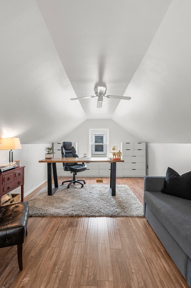 home office with wood finished floors, visible vents, baseboards, ceiling fan, and vaulted ceiling