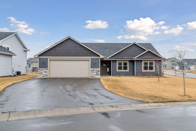 view of front facade featuring driveway, stone siding, a garage, and a front yard