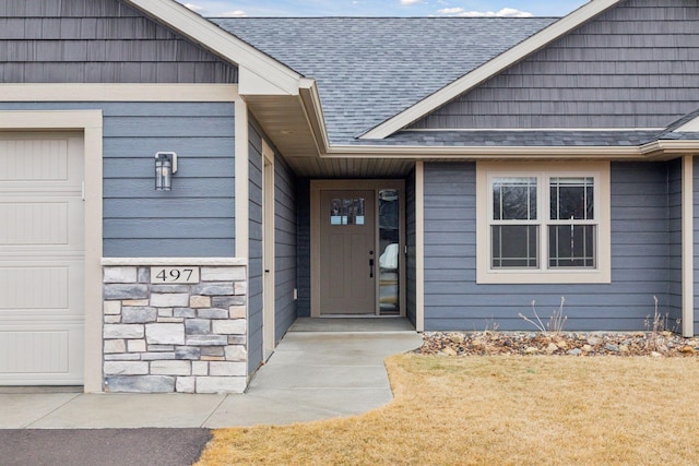 entrance to property featuring a garage, stone siding, and a shingled roof