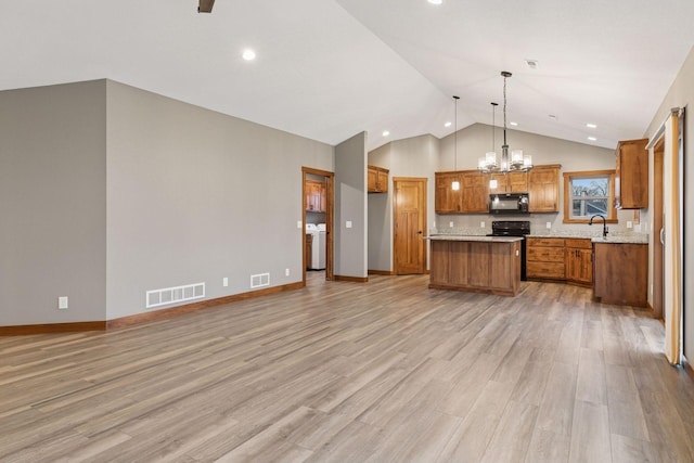 kitchen featuring visible vents, brown cabinets, open floor plan, black appliances, and a sink