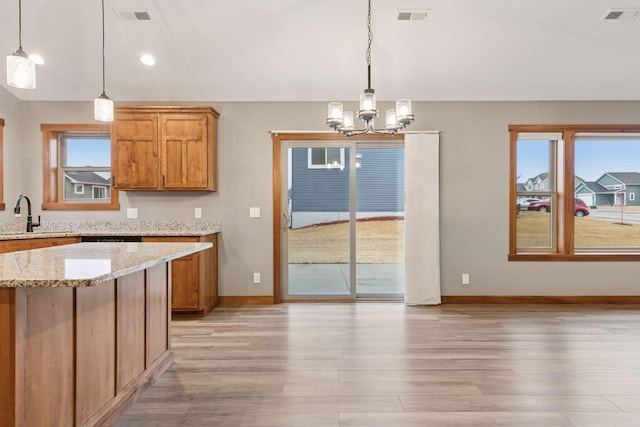 kitchen featuring vaulted ceiling, brown cabinetry, visible vents, and light wood-style floors