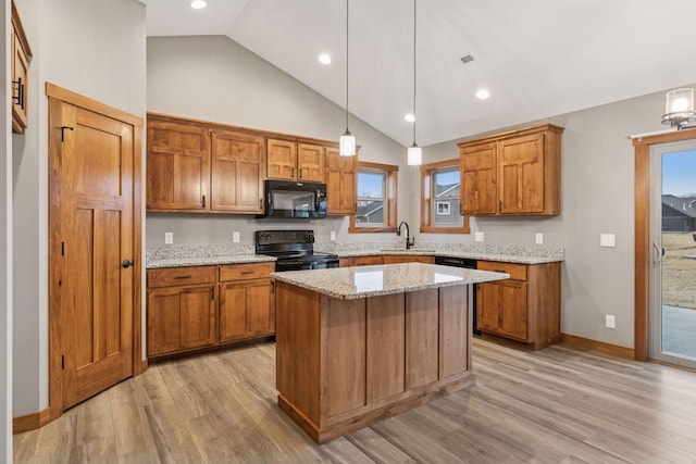 kitchen featuring black appliances, light wood finished floors, a sink, and brown cabinets