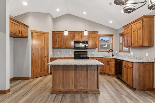 kitchen with brown cabinetry, light wood-style floors, light stone countertops, black appliances, and a sink