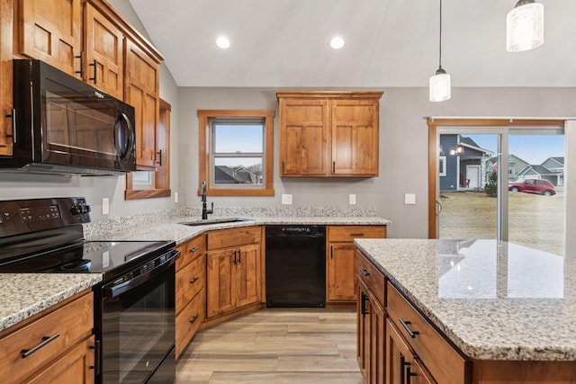 kitchen with a sink, vaulted ceiling, light wood-type flooring, black appliances, and brown cabinetry