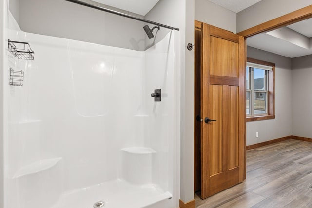 bathroom with walk in shower, baseboards, and wood finished floors