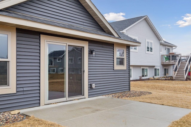 doorway to property featuring roof with shingles and a patio area