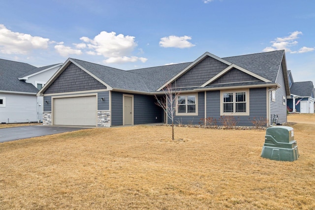 view of front of house with stone siding, aphalt driveway, roof with shingles, an attached garage, and a front yard