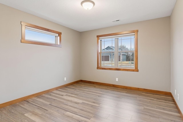 unfurnished room with plenty of natural light, visible vents, and light wood-style floors