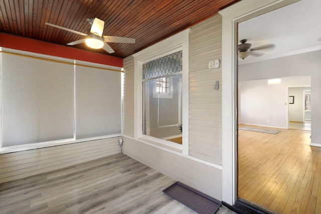 unfurnished sunroom featuring wood ceiling and a ceiling fan