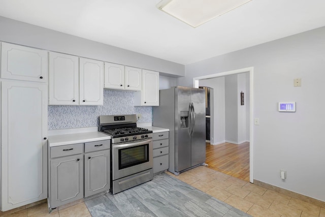 kitchen featuring tasteful backsplash, light countertops, gray cabinets, stainless steel appliances, and white cabinetry