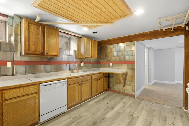 kitchen with light wood finished floors, dishwasher, light countertops, brown cabinetry, and a sink