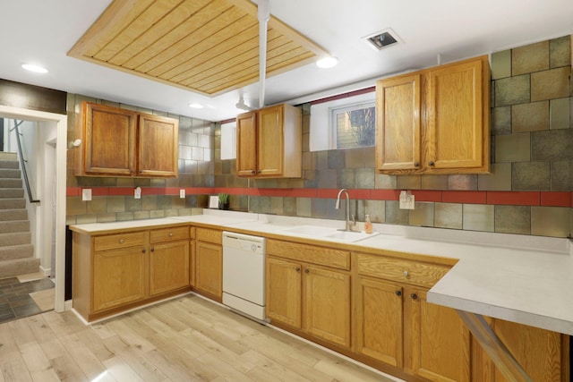 kitchen featuring visible vents, light wood-style flooring, a sink, dishwasher, and backsplash