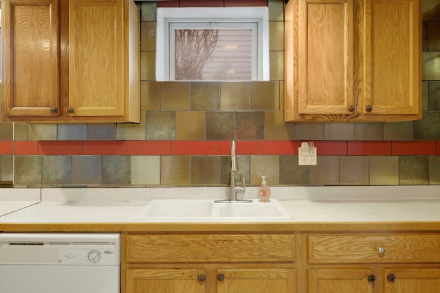 kitchen featuring dishwasher, light countertops, tasteful backsplash, and a sink