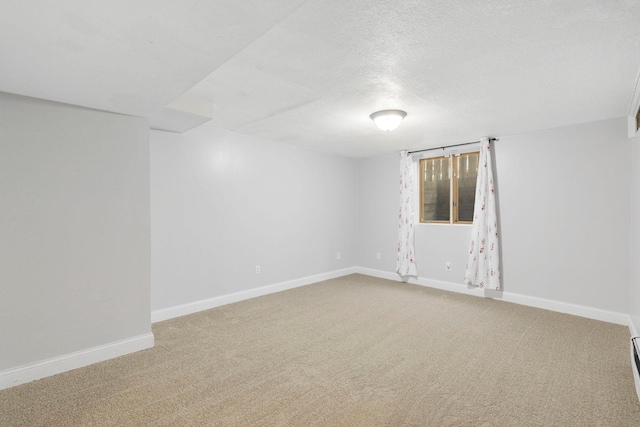 spare room featuring carpet flooring, baseboards, and a textured ceiling