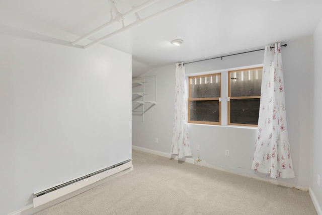 carpeted empty room featuring a baseboard heating unit and vaulted ceiling