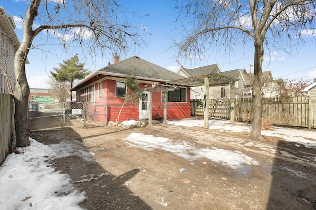 rear view of property featuring fence, a chimney, driveway, and a gate