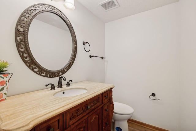 bathroom with toilet, a textured ceiling, vanity, and visible vents