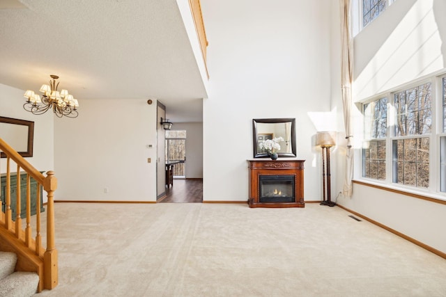 living room featuring carpet floors, stairs, baseboards, and a glass covered fireplace