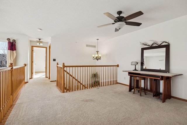 corridor with a textured ceiling, visible vents, carpet flooring, and an upstairs landing