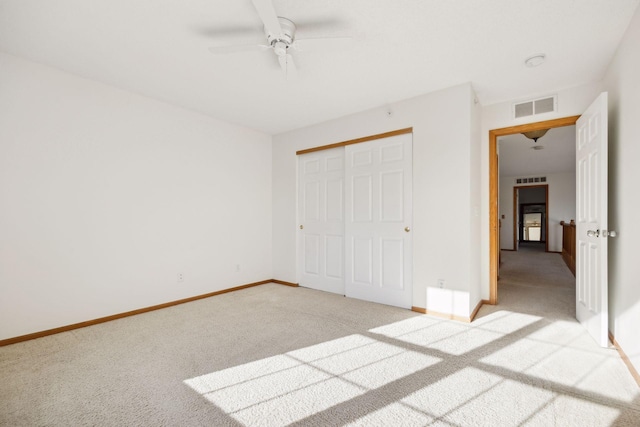 unfurnished bedroom featuring a closet, light colored carpet, visible vents, ceiling fan, and baseboards