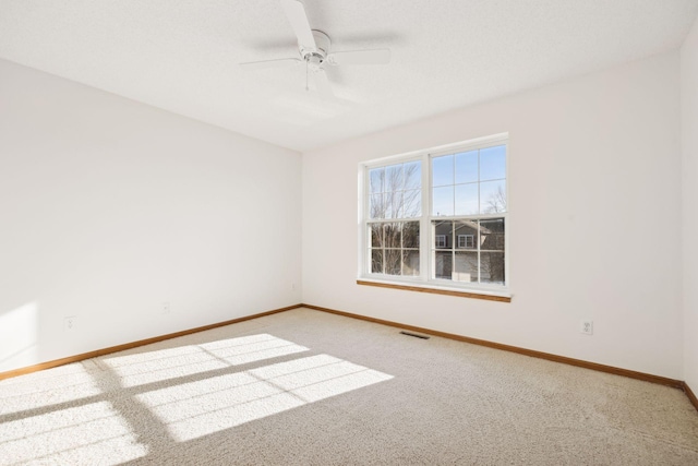 carpeted empty room featuring baseboards, visible vents, and a ceiling fan