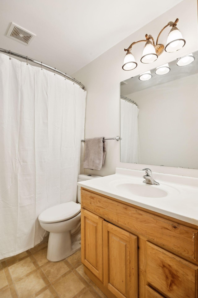 bathroom featuring toilet, vanity, and visible vents